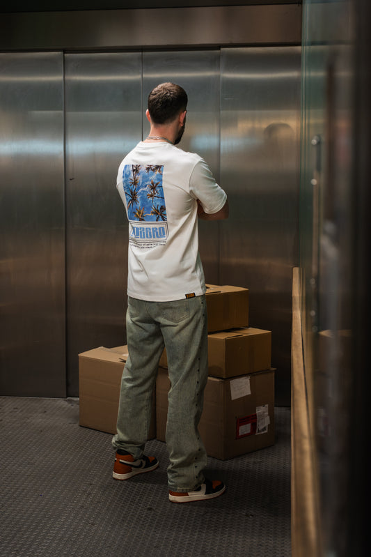 Coastal Dreams Tee in Off White – back view with upward palm tree sky photo print and 10 to Zero graphic