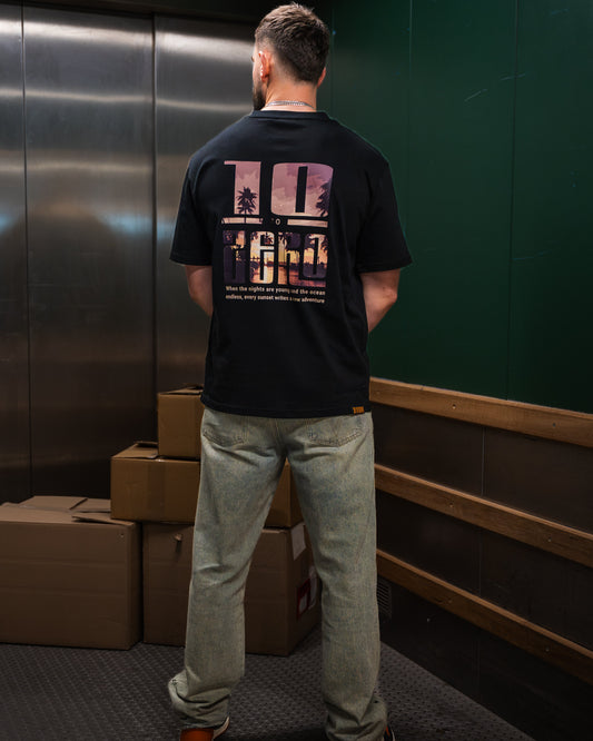 Sunset Adventures Tee in Black – back view with sunset palm tree photo fill inside 10 to Zero letters