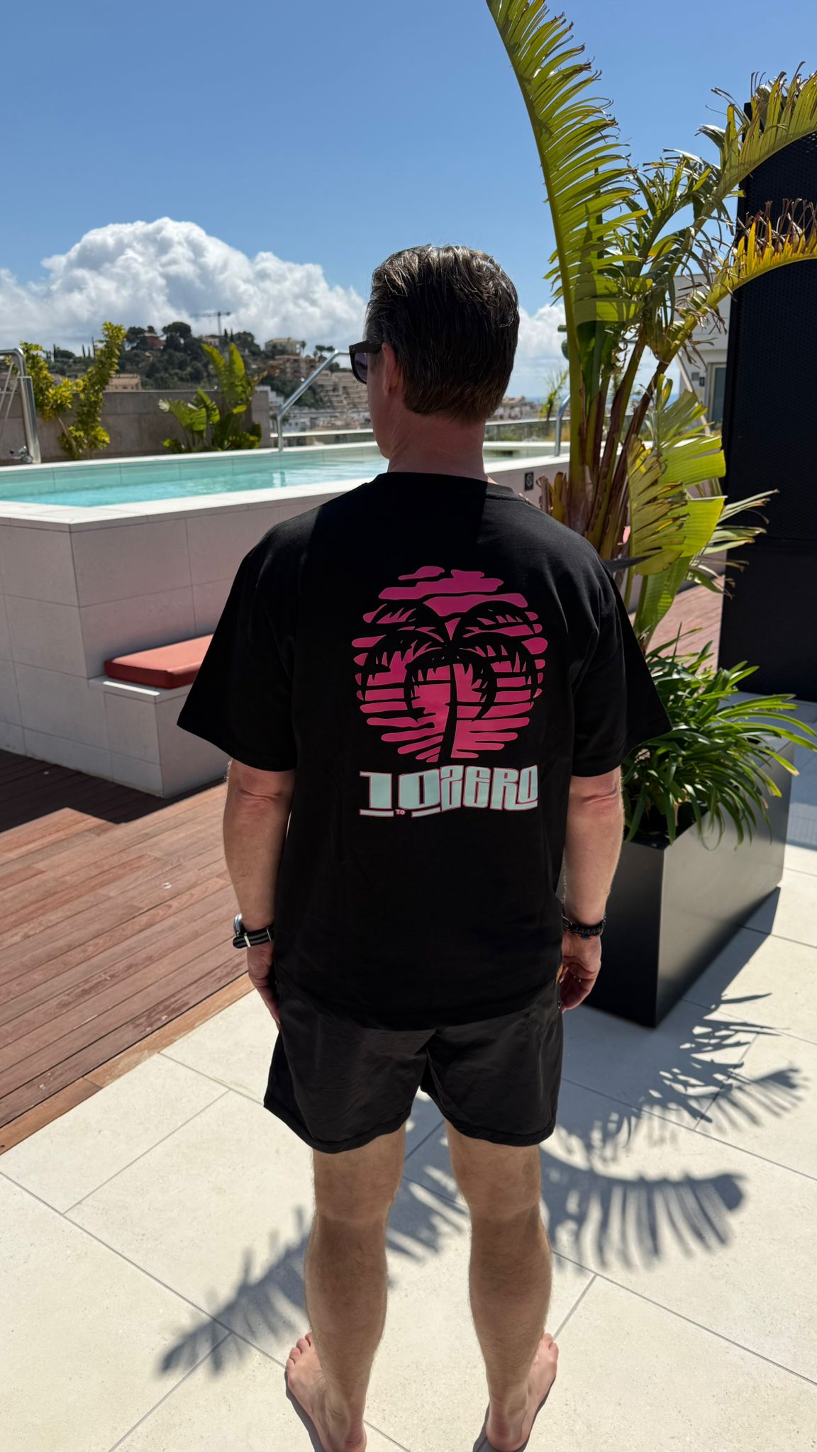 Palm Society Tee in Black – back view with retro sunset palm tree print in pink and mint, 10 to Zero graphic